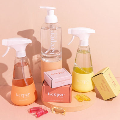Line up of 3 different bottles: Bathroom spray bottle made of glass with peach coloured silicone sleeve, Multi-purpose spray bottle made of glass with peach coloured silicone sleeve, Multi-purpose spray bottle made of glass with yellow coloured silicone sleeve, clear glass hand soap bottle. Including dissolvable pod refills.